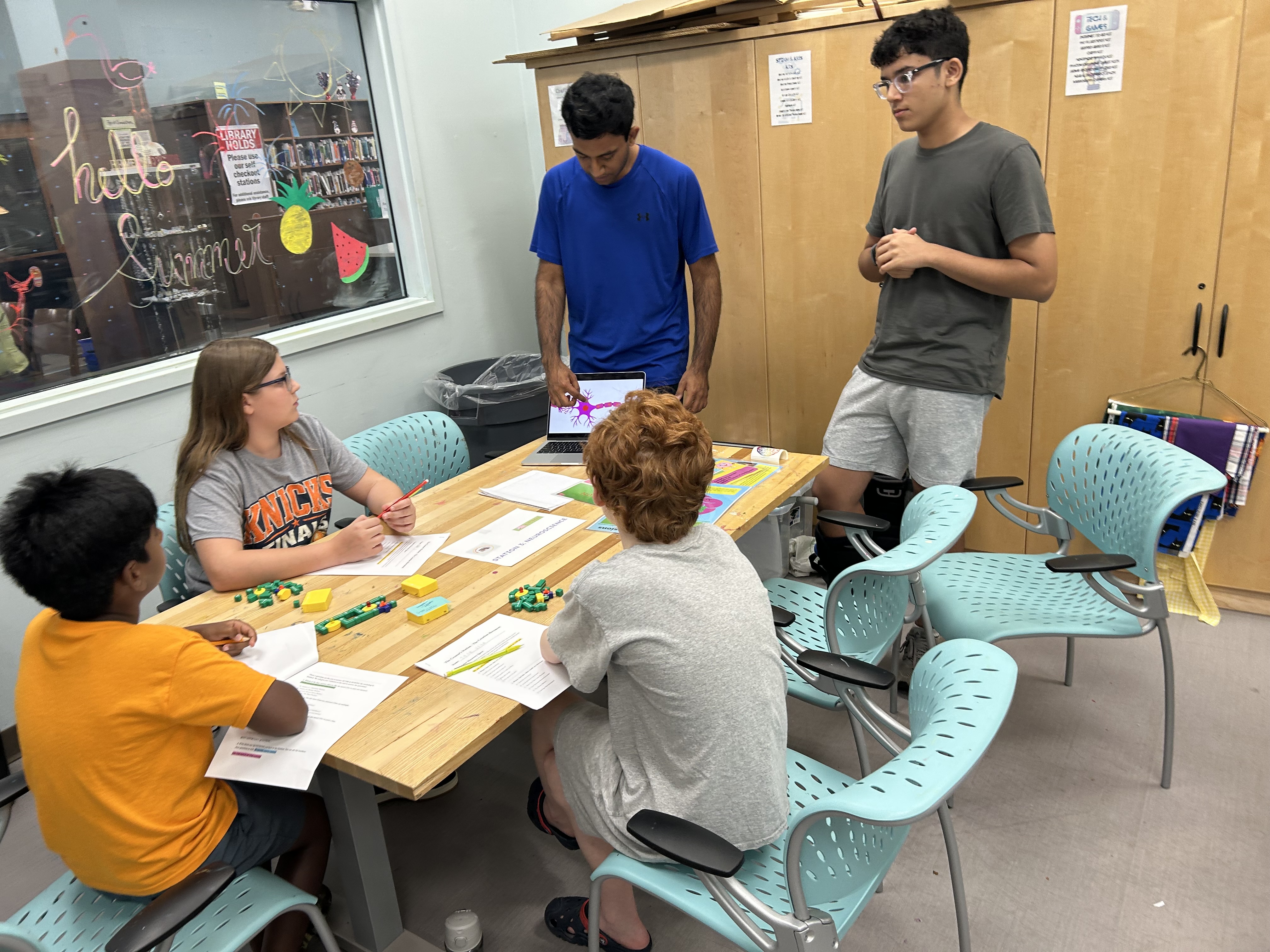 A mentor leading students through a hands-on workshop activity